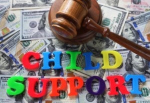 Letters spelling"Child Support" sittong on top of a stack of cash next to a judges gavel