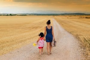 Mother and daughter walking down dirt road