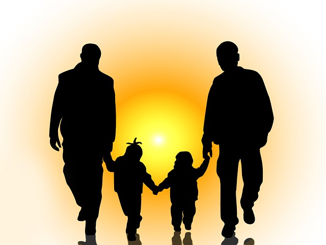 Silhouette of two dads walking with their little children.