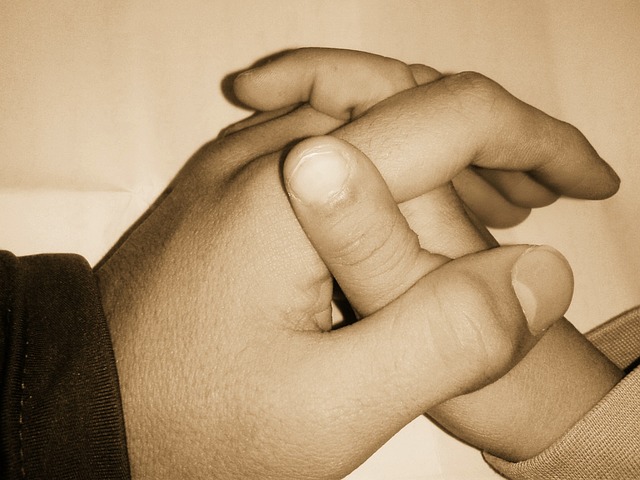 A close up sepia toned picture of an adult's hand holding a child's hand.