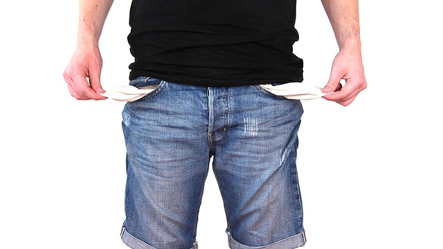 A picture of a man wearing jeans, pulling the inside of his pockets out to prove that he has no money.