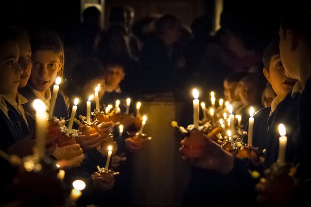 A group of children standing together, holding candles in the darkness