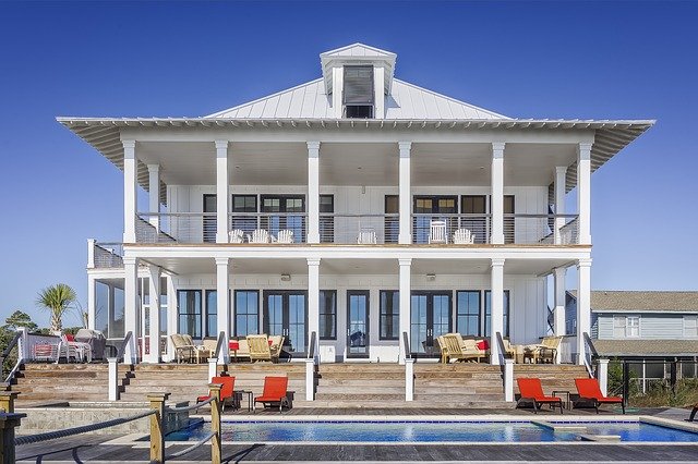 A large home, possibly a vacation home, with a pool and reclining chairs on the deck.